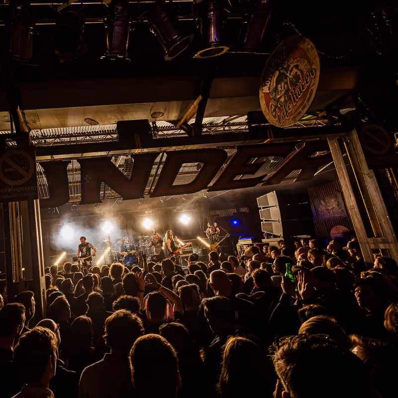 Een band speelt voor een vol publiek onder het bord van Thunderbolt