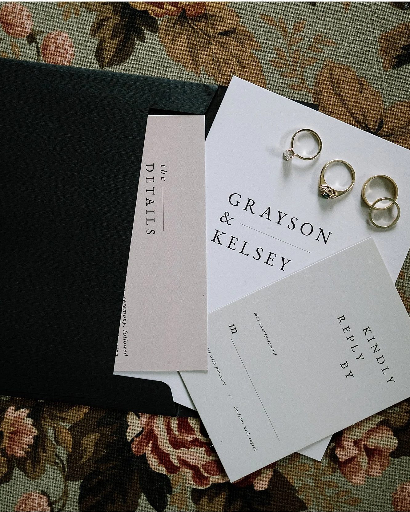 Wedding invitations and rings laid on floral fabric