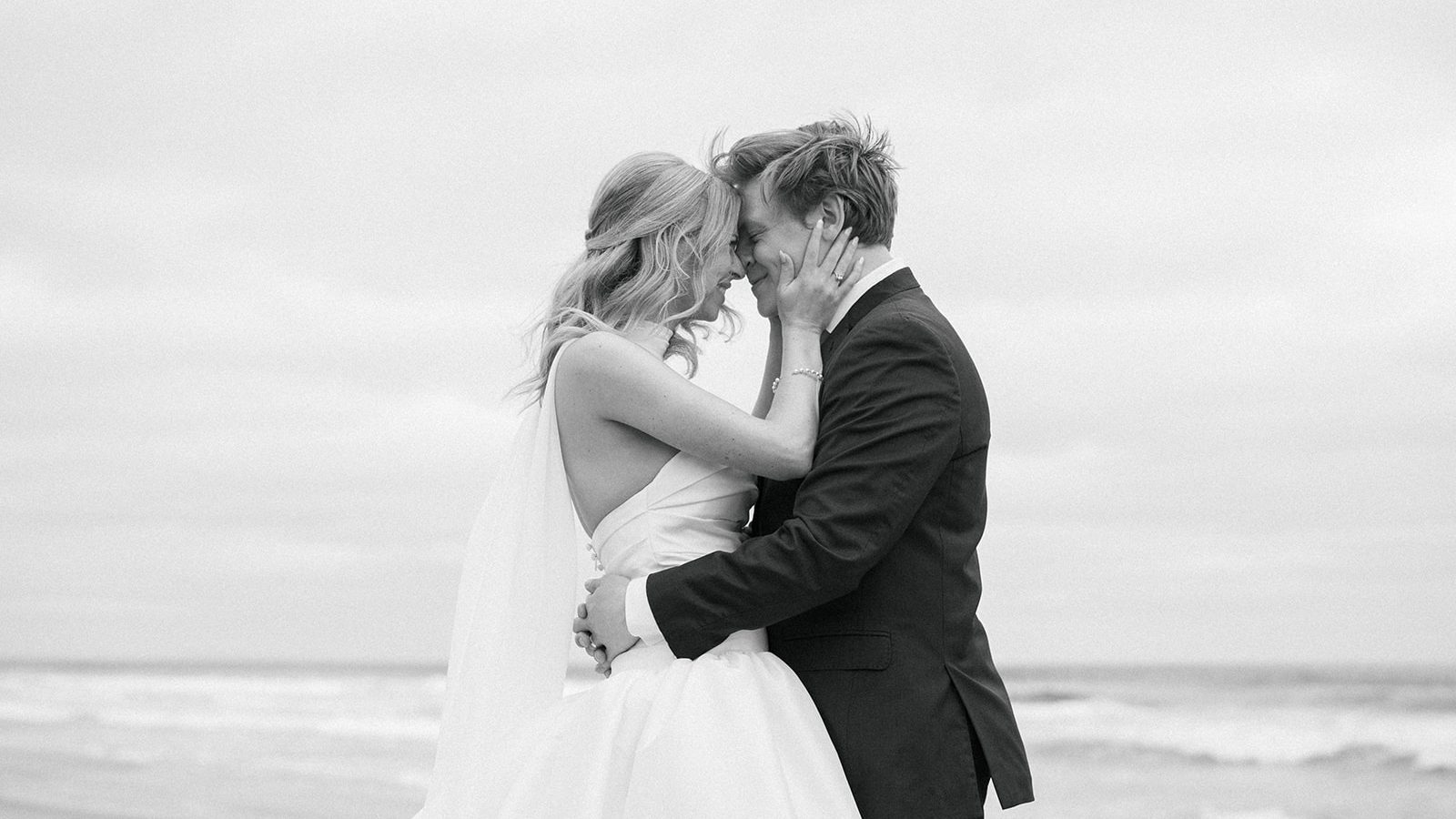 Black and white frame of the couple with foreheads together on a quiet beach