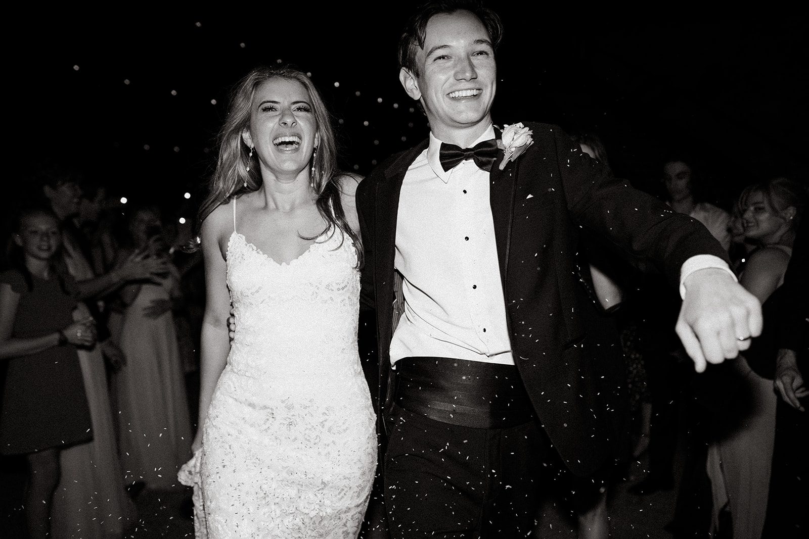 Black and white frame of the couple laughing as they leave through guests holding sparklers