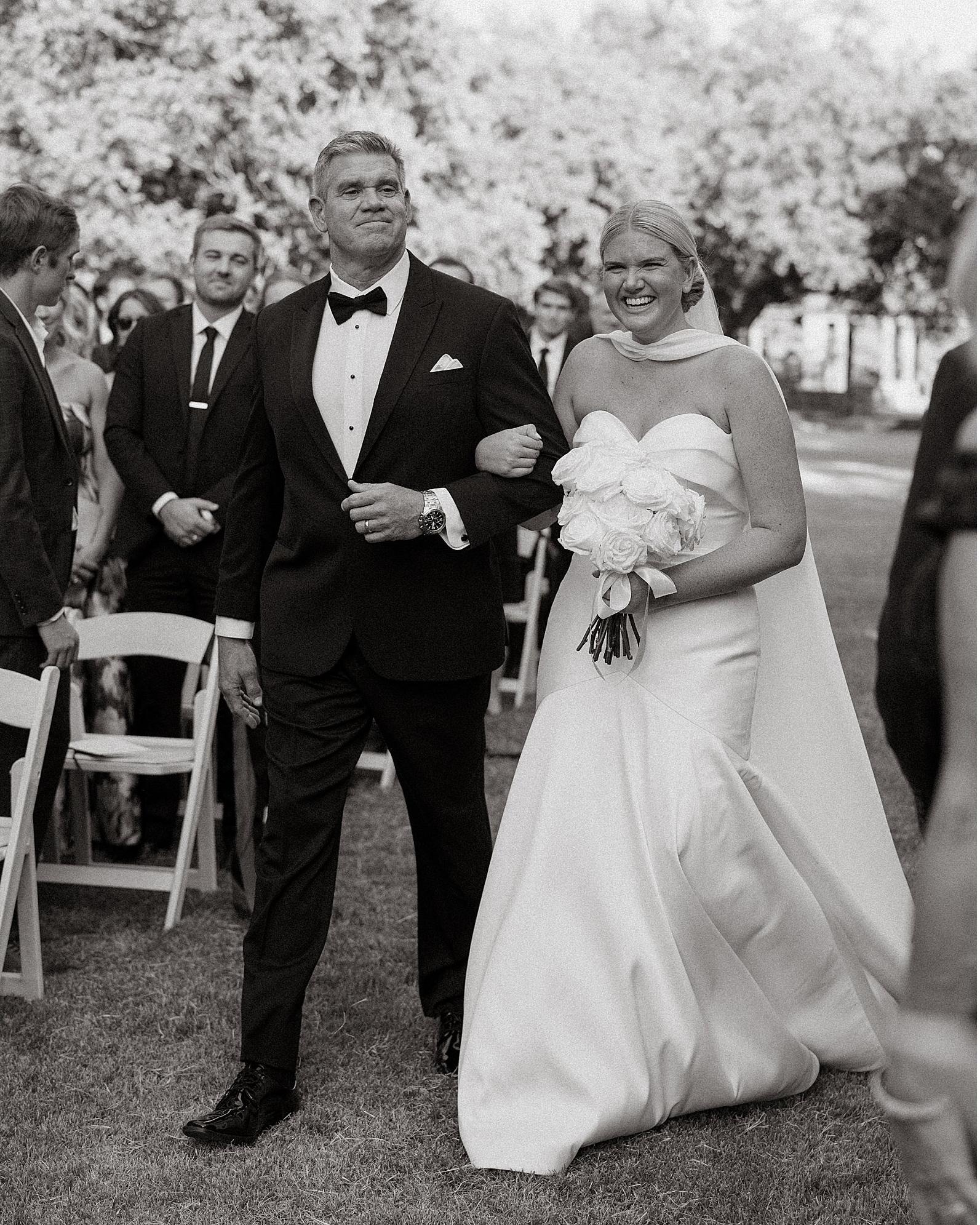 Black and white, the bride's father walking her down the aisle