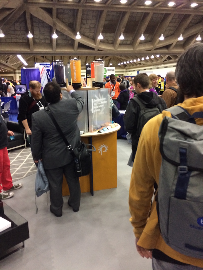People interacting with booth at DrupalCon