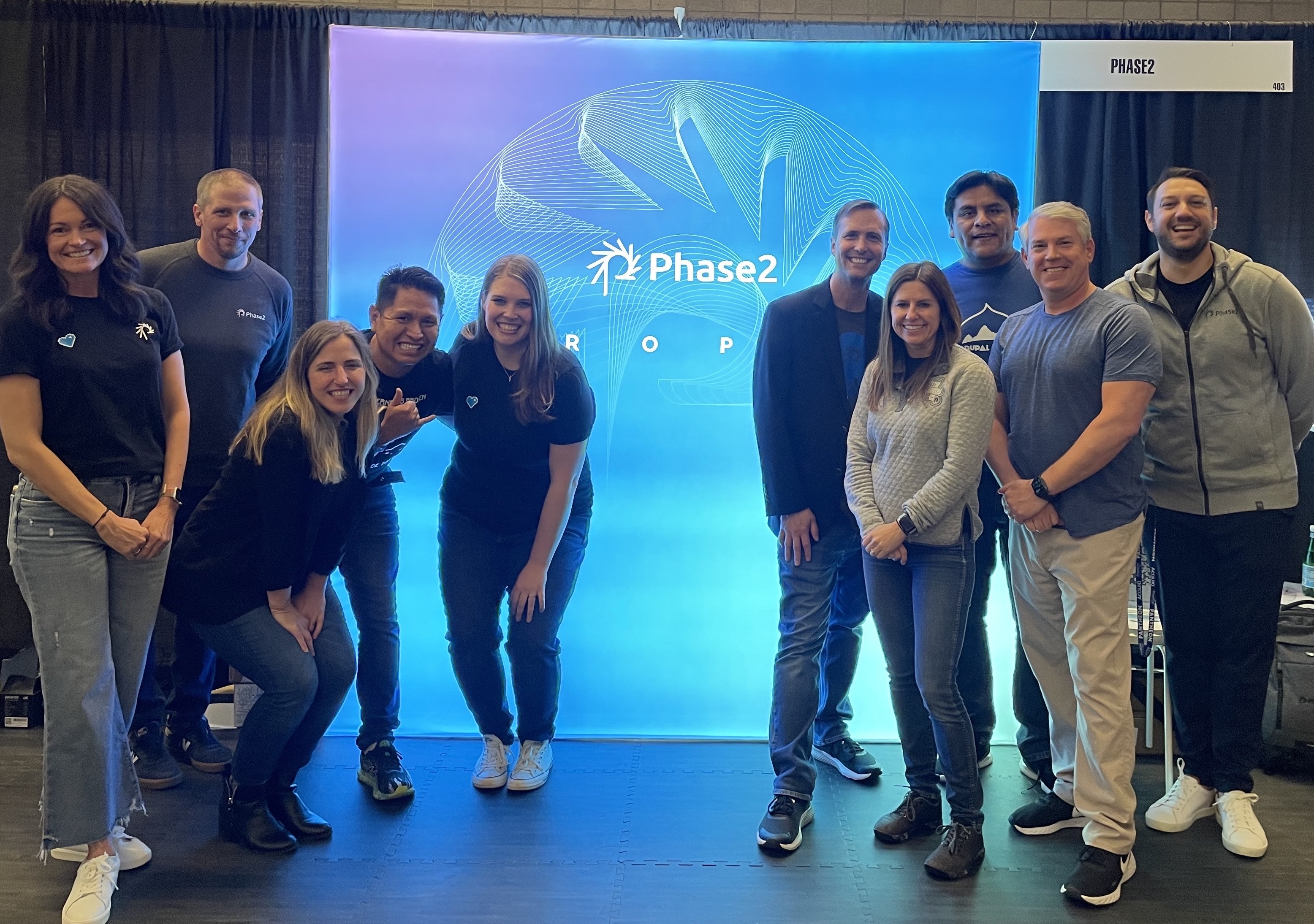 Ten people posing in front of Phase2 sign