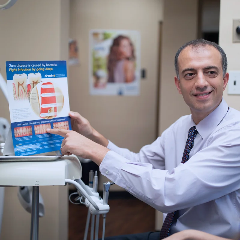 Dr. Ilya Ames explaining a dental chart during a free patient consultation at Queens Central Dental in Jackson Heights