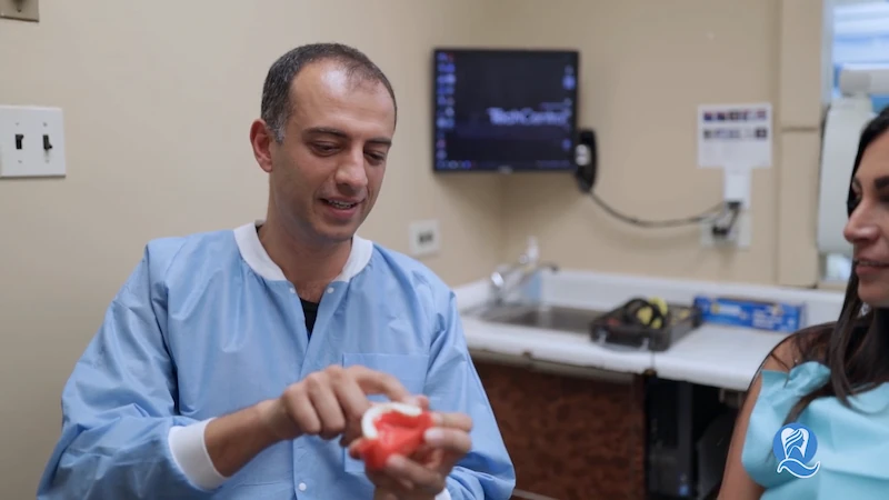 Dr. Ilya Ames explaining treatment with a dental model to a patient at Queens Central Dental in Jackson Heights