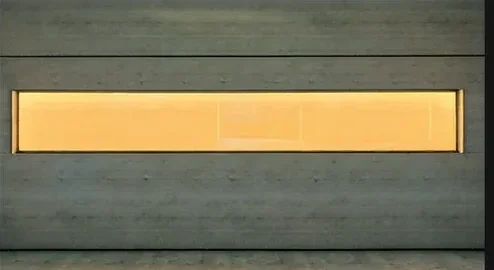 Inside a generated room: a wall of pale board-marked concrete with a long window of warm amber light