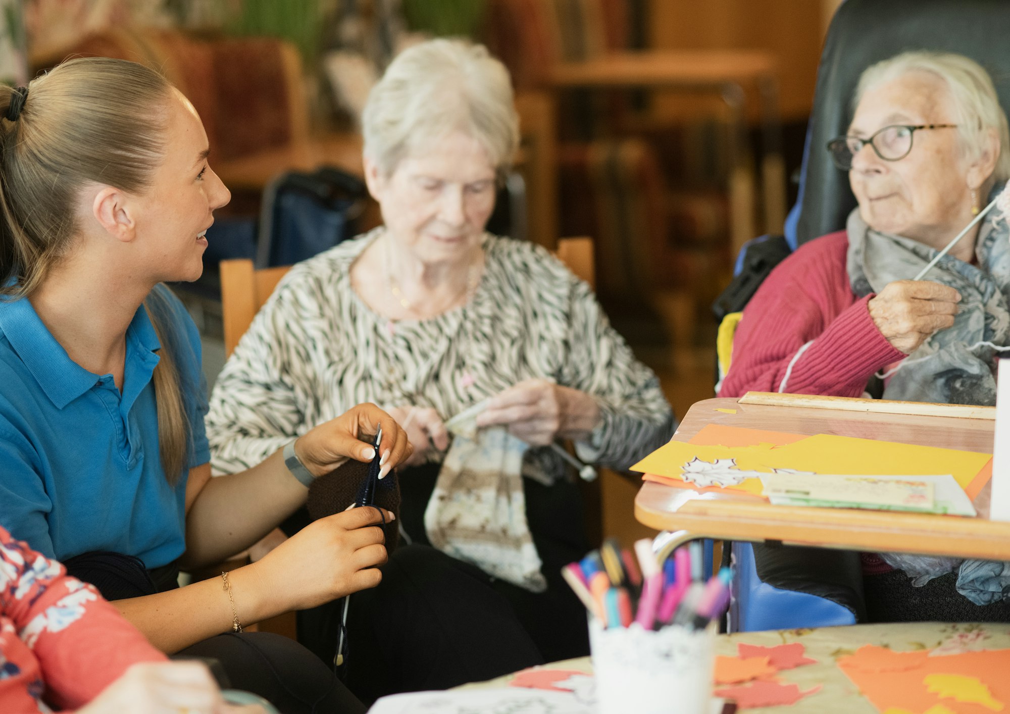 Residents enjoying a knitting activity with a team member in a senior living community