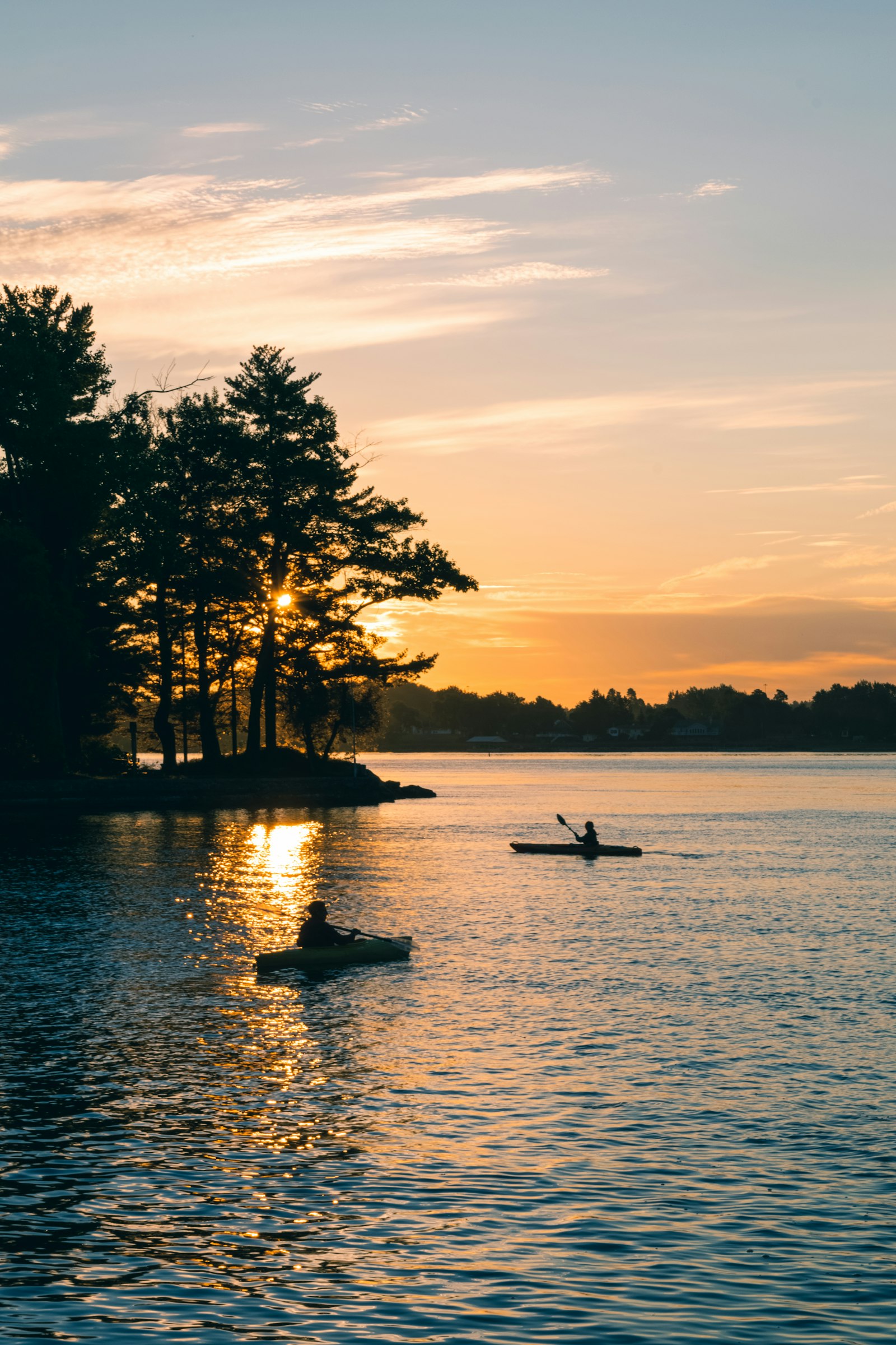 Two kayakers paddling at sunset among the islands