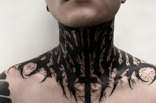 Blackwork neck and collarbone tattoo with sharp organic shapes and a cross