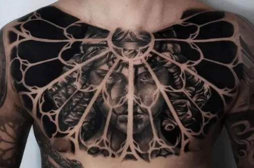 Chest tattoo of a classical face framed by a blackwork gothic window