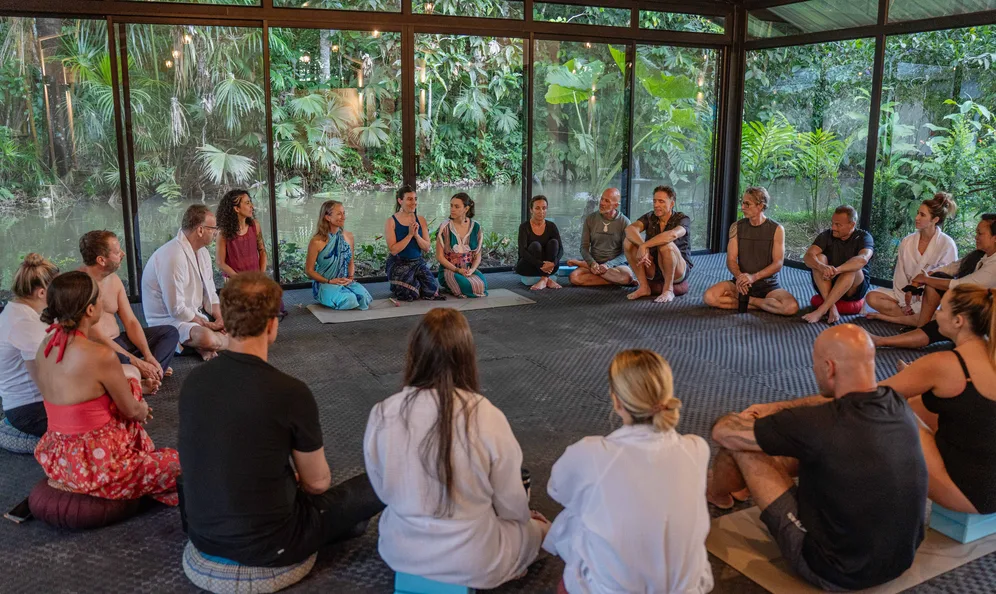 Group circle session inside a glass jungle pavilion