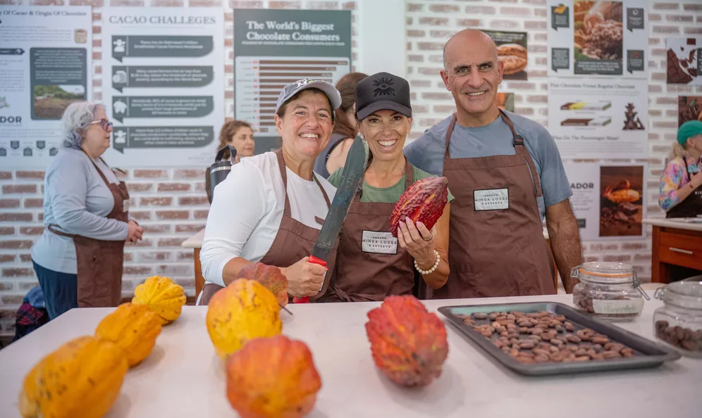 Guests at a cacao workshop holding fresh cacao pods