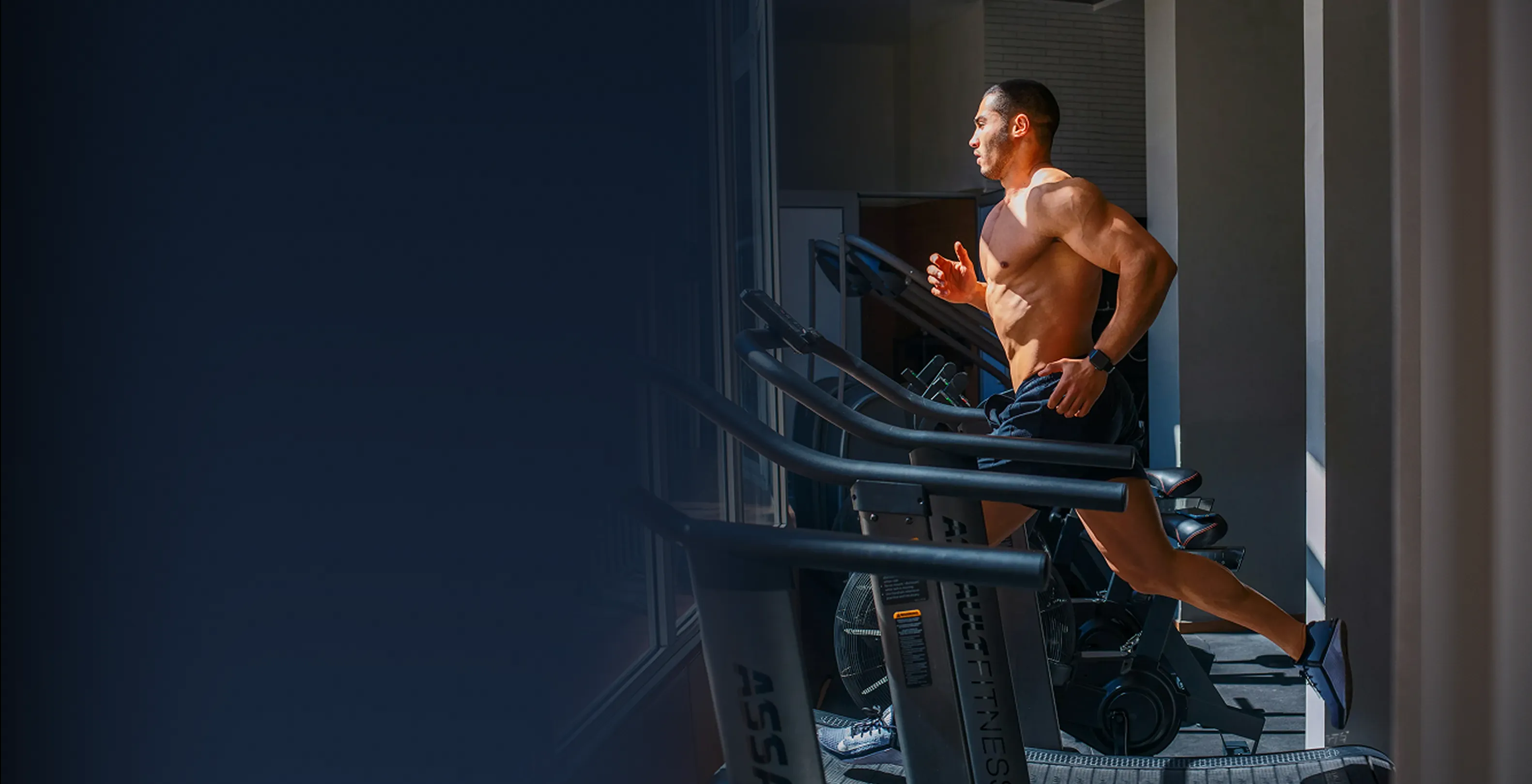 Man running on a treadmill in a sunlit gym