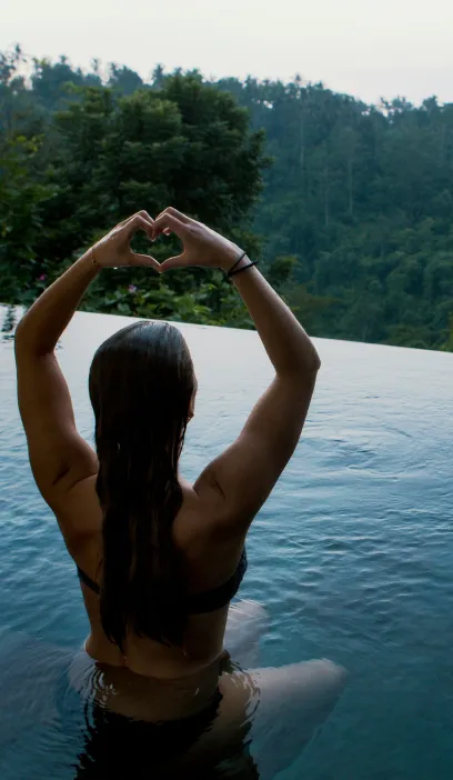 Woman in an infinity pool facing the jungle