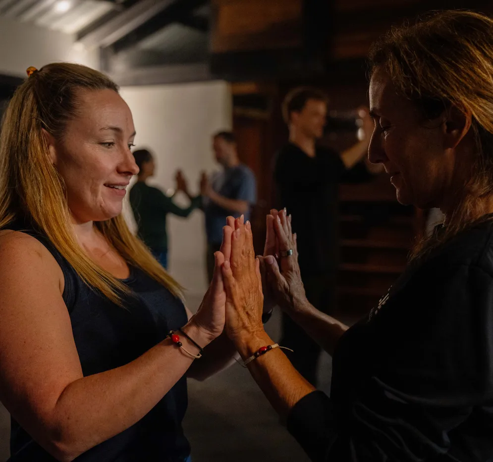 Two retreat guests pressing their palms together during a partner exercise
