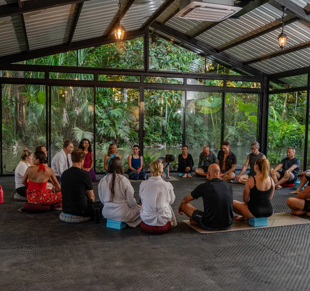 Group session inside a glass pavilion surrounded by rainforest
