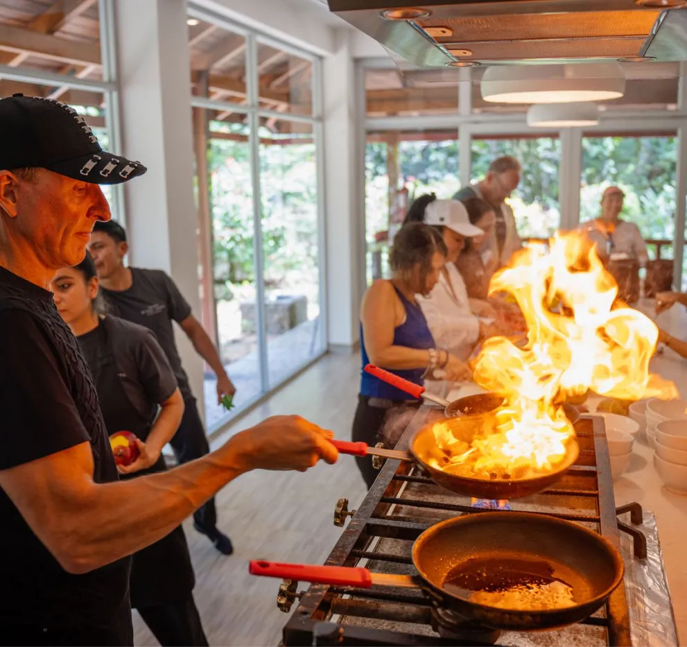 Chef flambéing in an open kitchen with guests