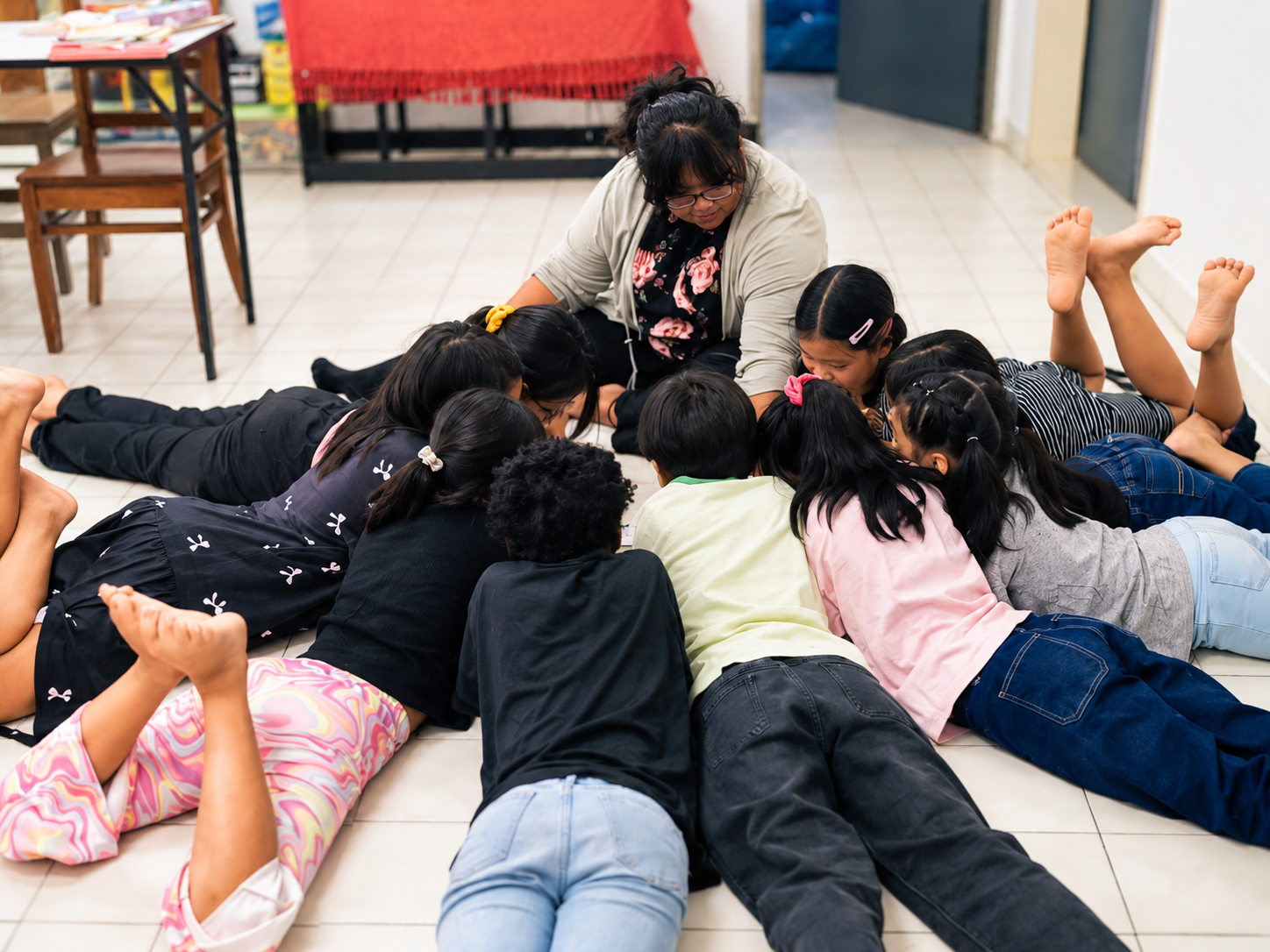 A group of children gathering around an adult in a learning activity
