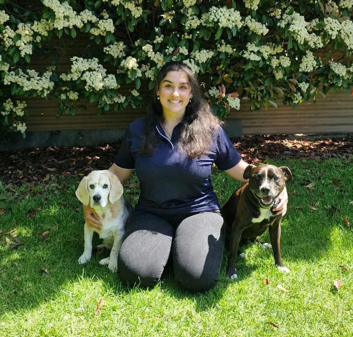 Jess kneeling on grass with her dogs