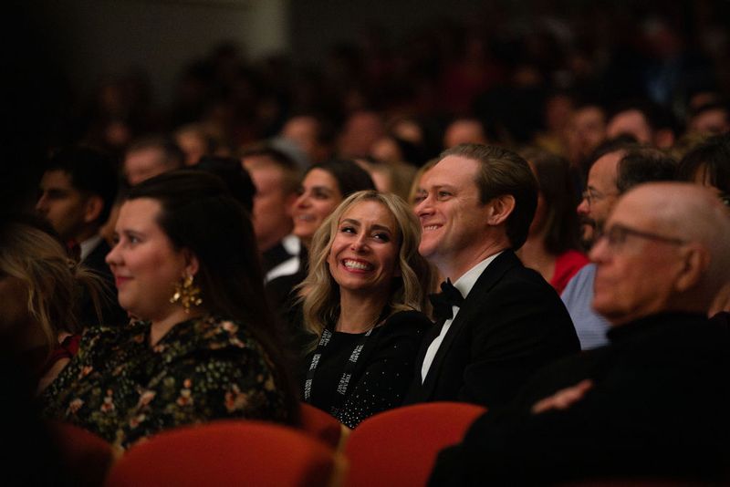 An audience seated before the film