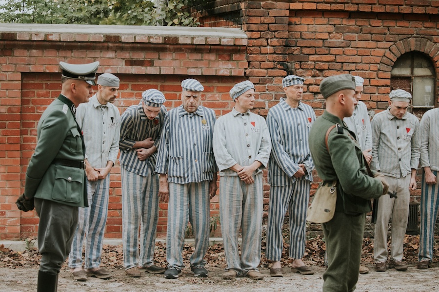 Prisoners in striped uniforms line up before guards on the set of Triumph of the Heart