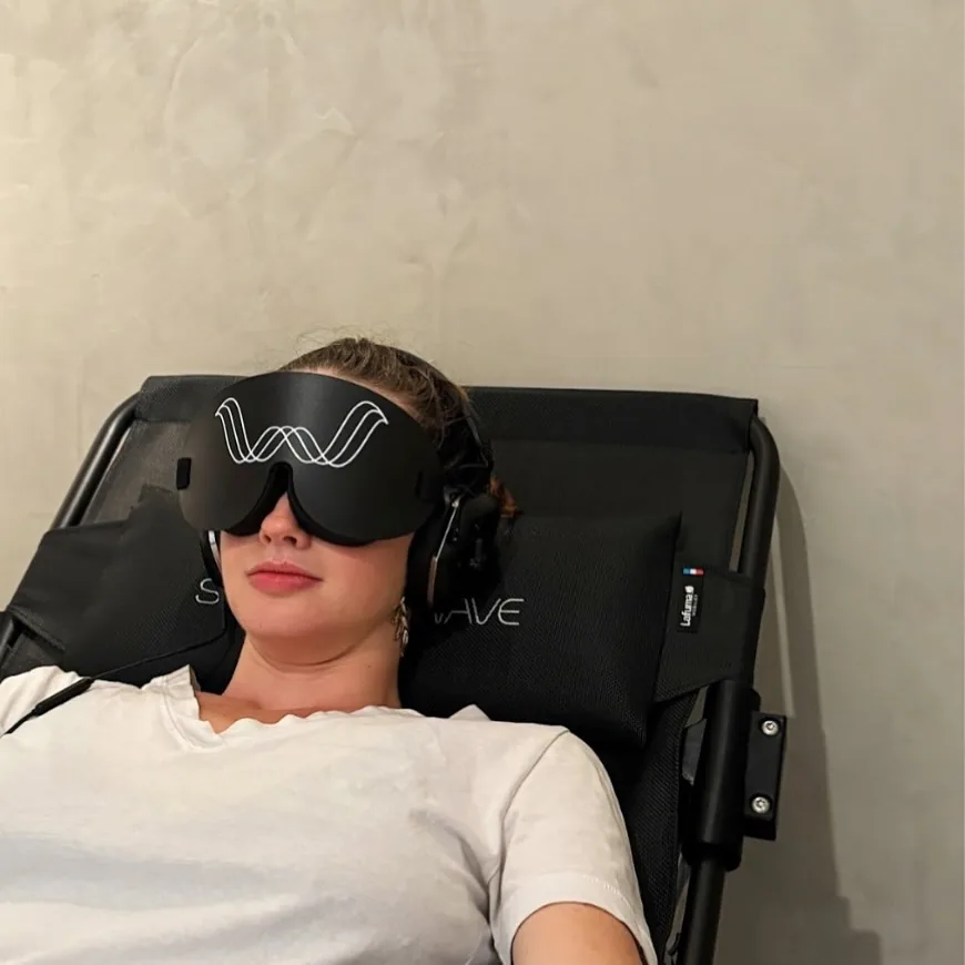 Une femme installée dans le fauteuil ShiftWave, un masque sur les yeux et un casque sur les oreilles.