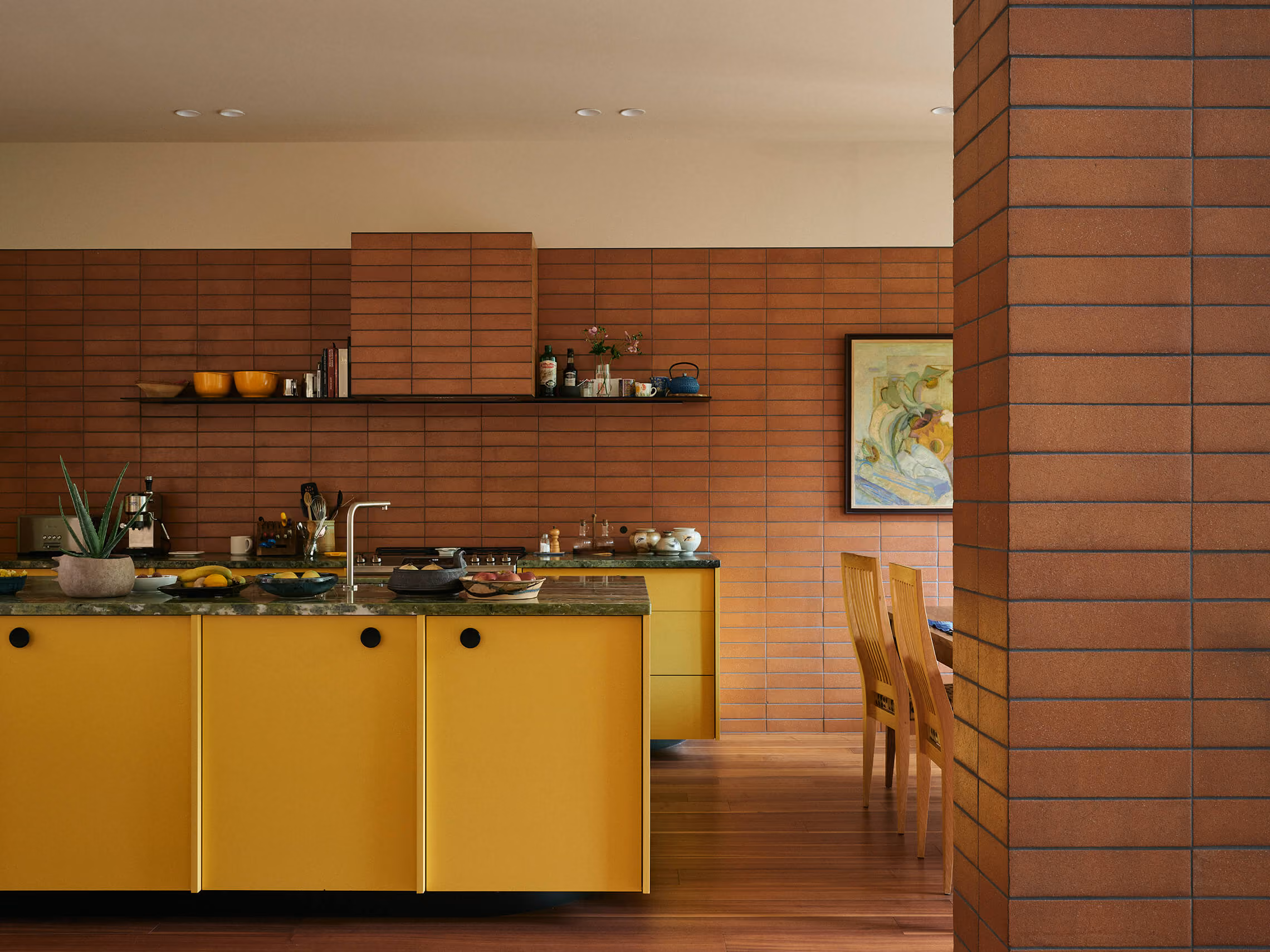 A kitchen with yellow cabinets and a green marble island