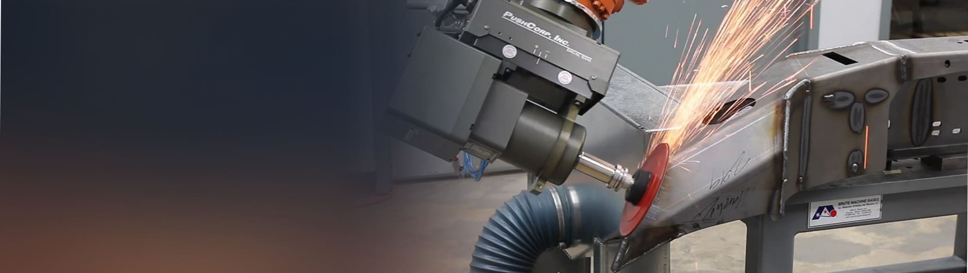 PushCorp force-compliant tool on a robot arm grinding a steel weld, throwing sparks