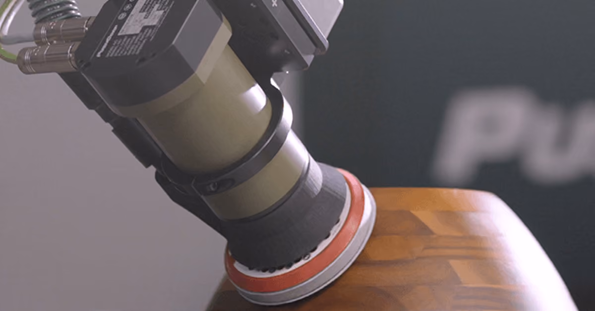 A PushCorp random orbital sander on a robot arm smoothing a curved wooden panel