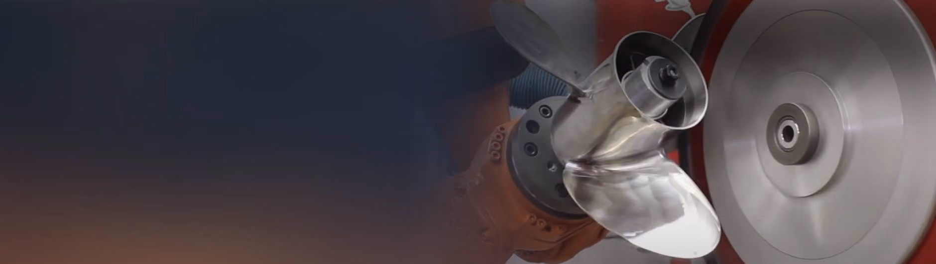 A PushCorp robot arm running a force-controlled abrasive wheel across a stainless steel boat propeller
