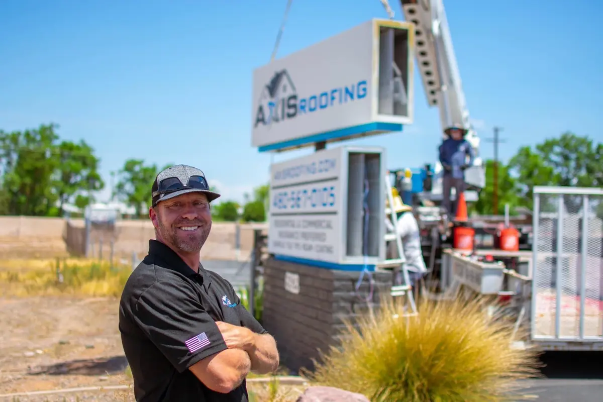 Bill Crook, the owner of Axis Roofing, stands in front of the new Axis Roofing Sign at the Mesa Office