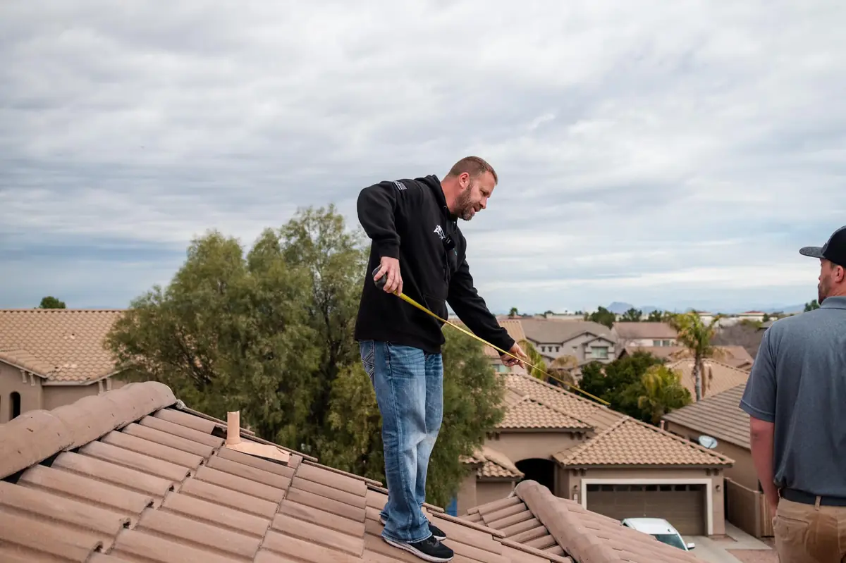 Owner of Axis Roofing, Bill Crook, inspecting a tile roof while training new roofers in Gilbert, Arizona