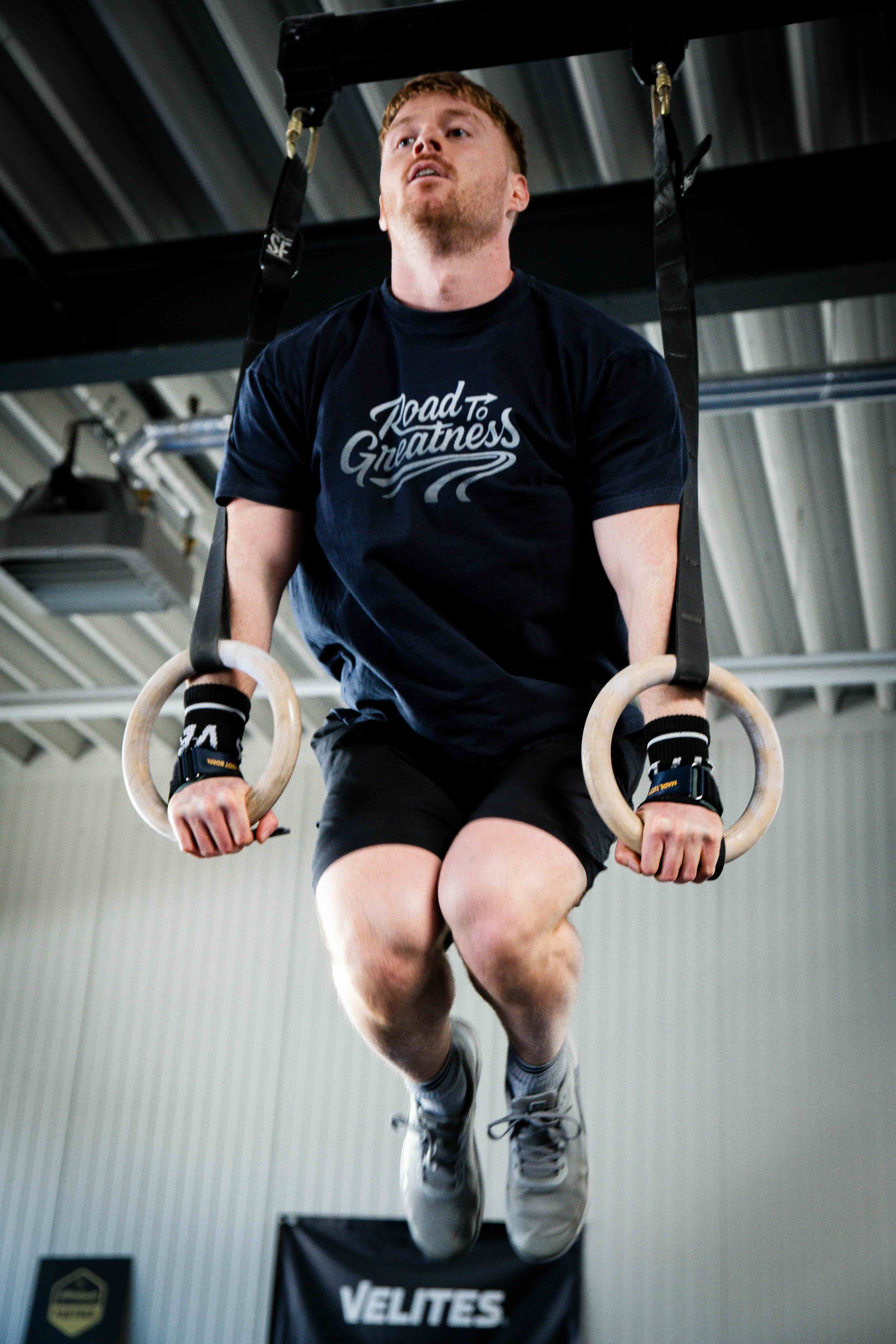 Athlet im Road to Greatness Shirt bei einem Muscle Up an den Ringen