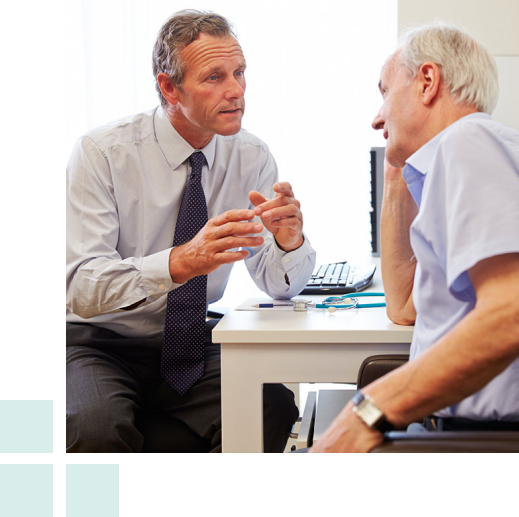 A man in a suit engages in conversation with an older gentleman, both appearing attentive and engaged in discussion.