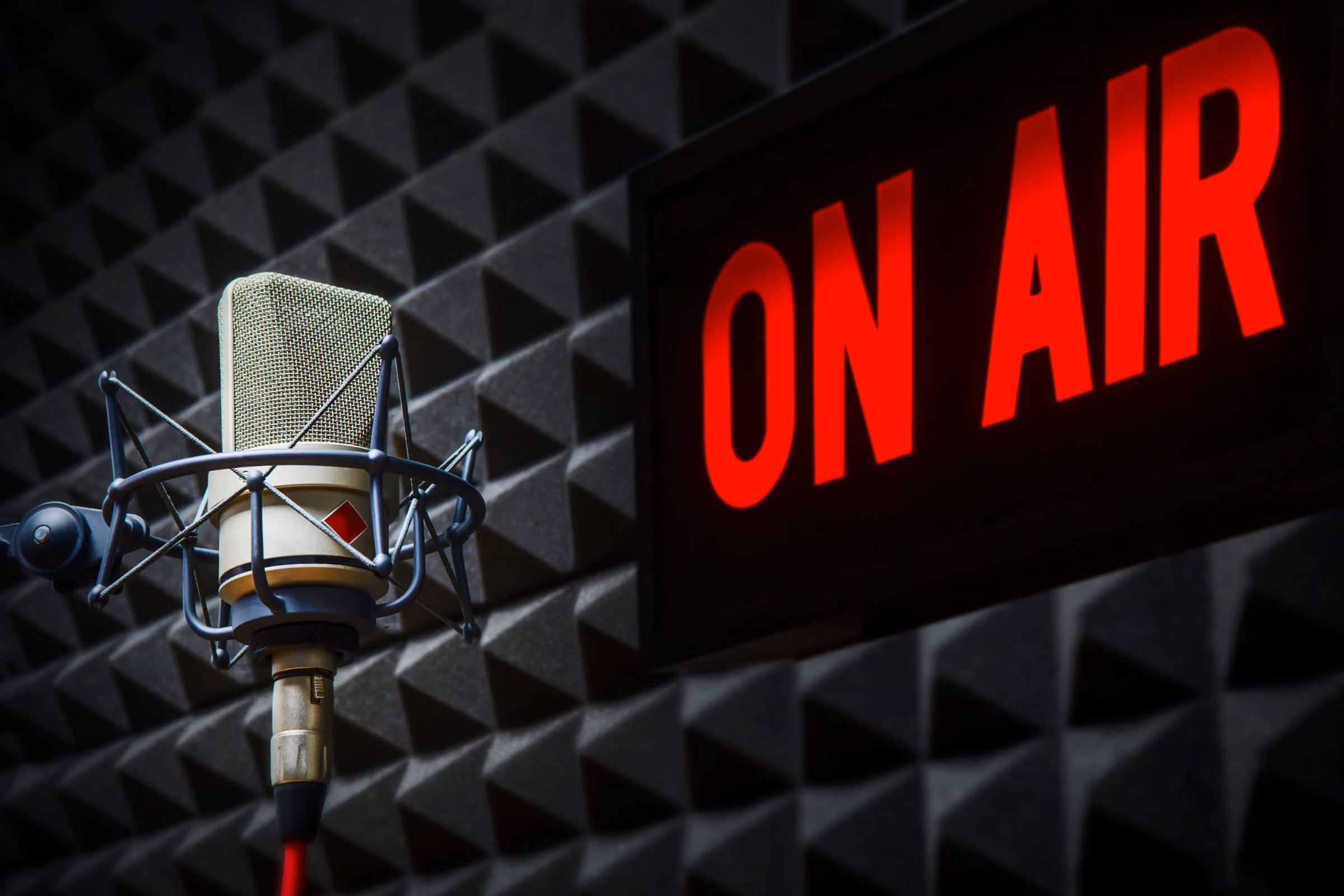 A studio microphone in front of a lit On Air sign.