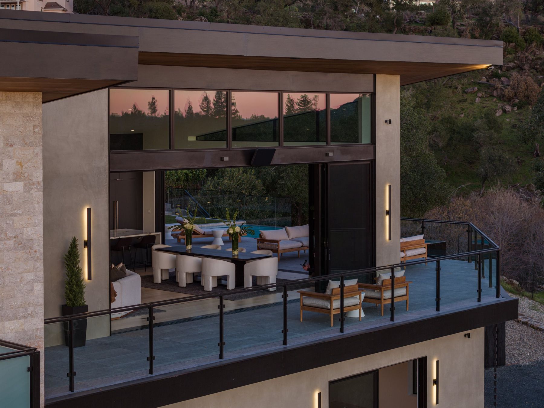 A lit dining deck on a modern hillside home at dusk, San Francisco Bay Area. Twilight real estate photography by Lumiful Media
