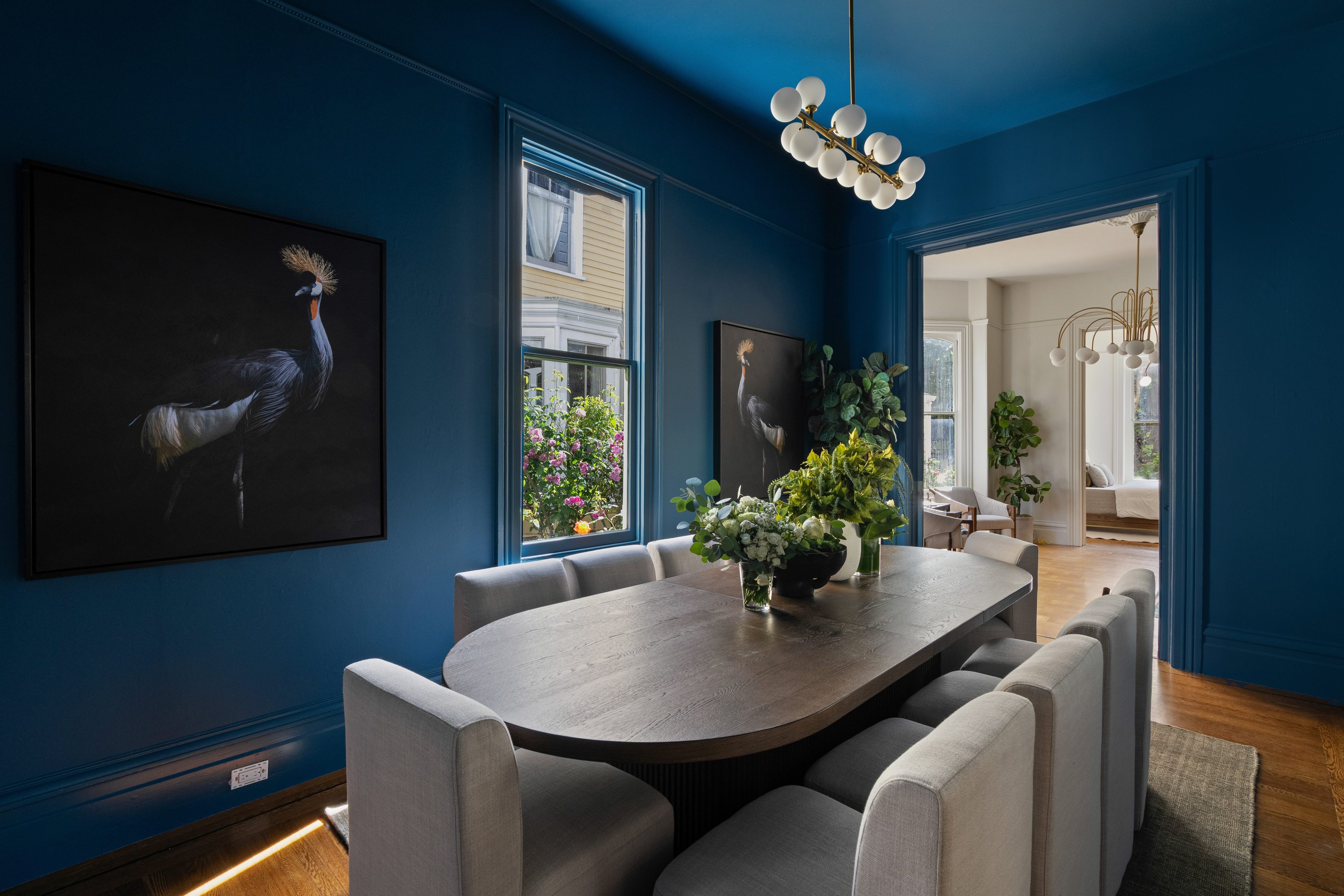 A Victorian dining room painted deep blue, with a painting of a crowned crane, San Francisco. Editorial interior photography by Lumiful Media