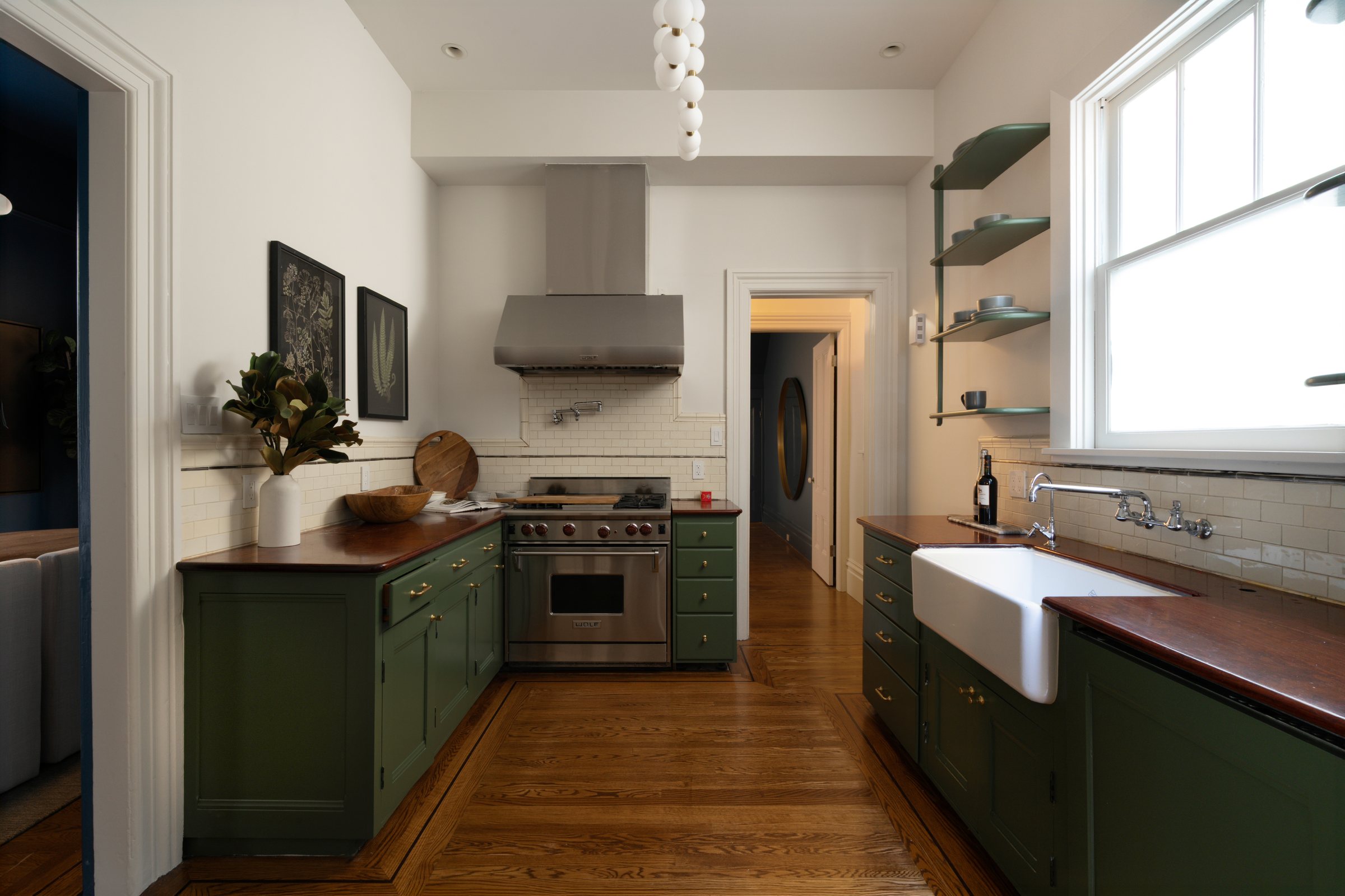 A kitchen with green cabinets, a farmhouse sink and open shelves, San Francisco Bay Area. Editorial interior photography by Lumiful Media