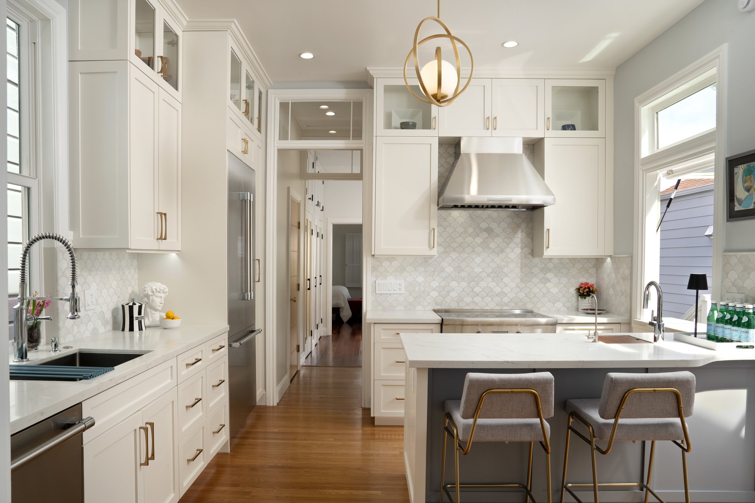A white kitchen with a brass pendant and marble counters, San Francisco Bay Area. Editorial interior photography by Lumiful Media
