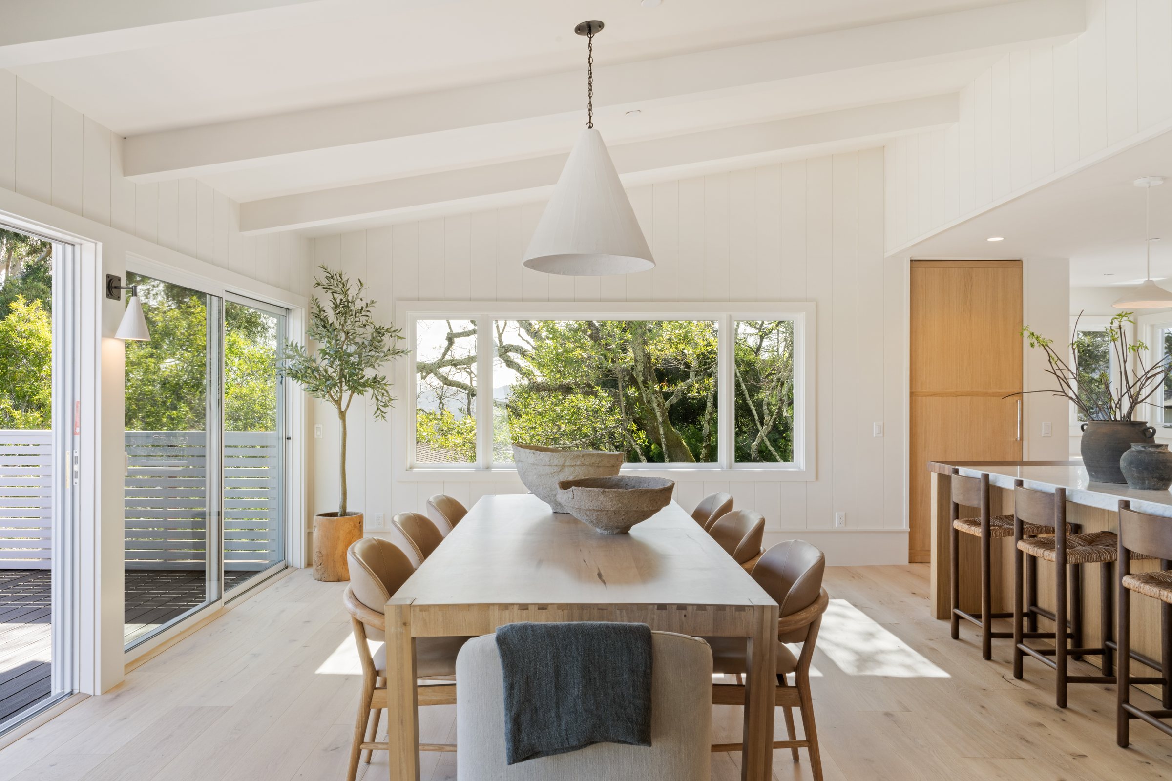 A long dining table under a white pendant with windows to the trees, San Francisco Bay Area. Real estate photography by Lumiful Media