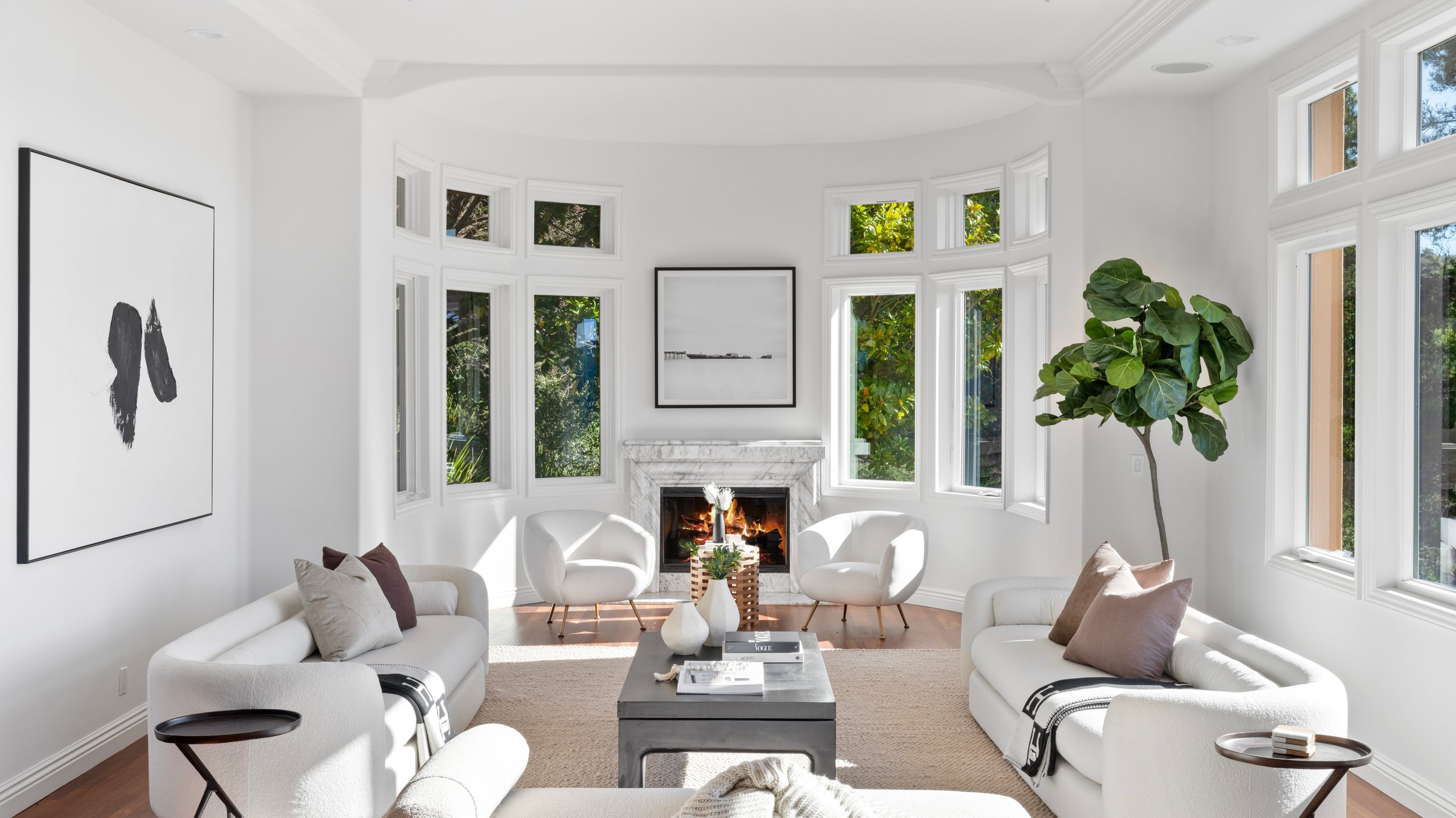 A white living room with a fireplace and bay windows, San Francisco Bay Area. Real estate photography by Lumiful Media