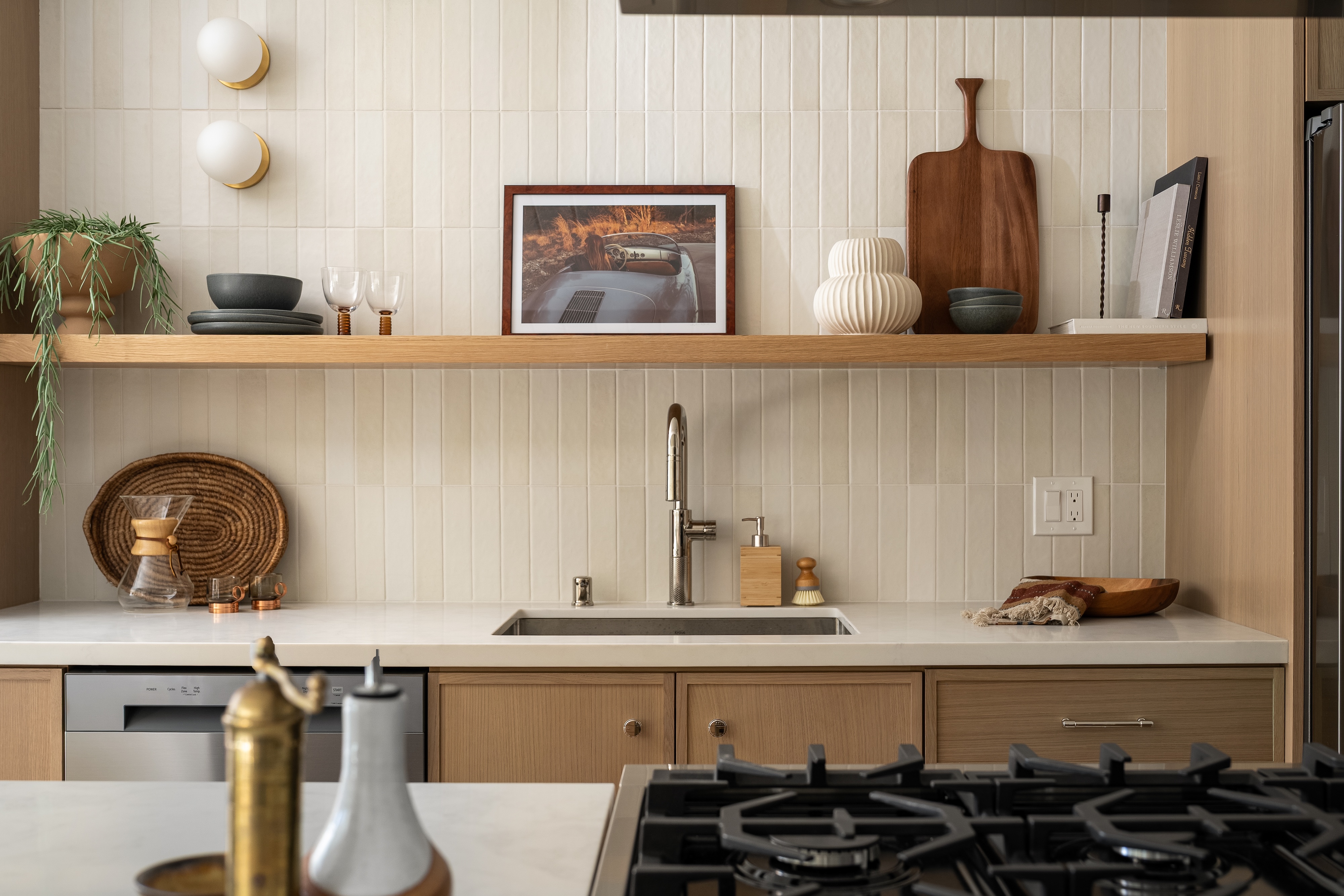 A kitchen with an oak open shelf, handmade tile and a brass faucet, San Francisco Bay Area. Real estate photography by Lumiful Media