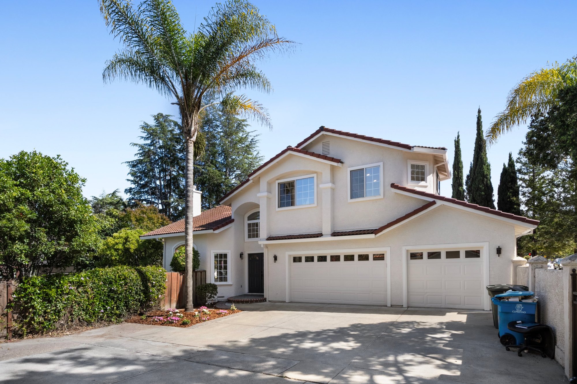 A stucco home with a tile roof and palm trees by day, Cupertino. Real estate photography by Lumiful Media