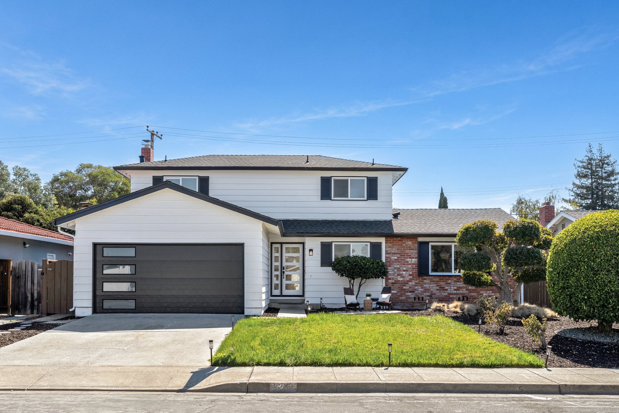 A two story home with white siding and a black garage door by day, San Francisco Bay Area. Real estate photography by Lumiful Media