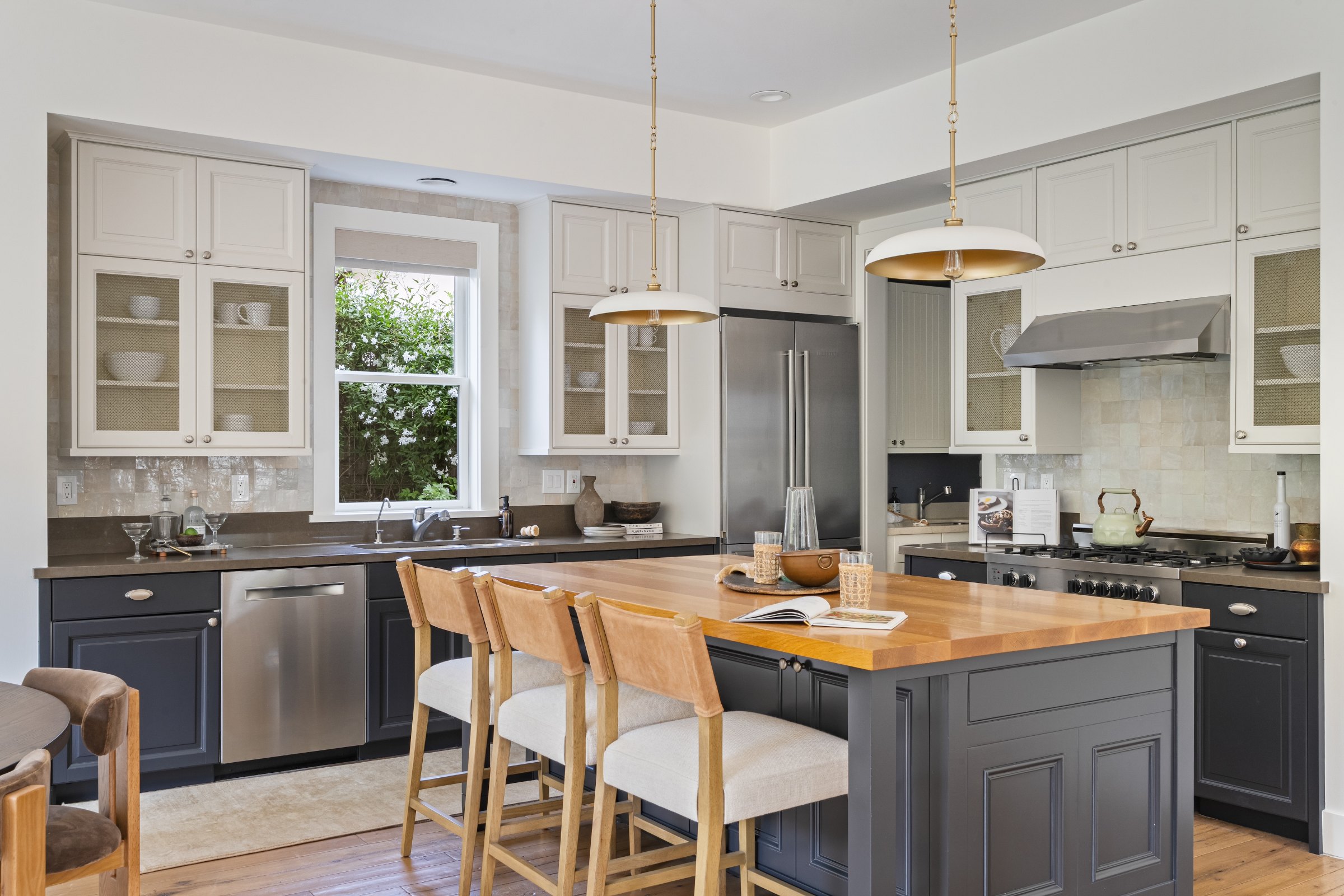A kitchen with white cabinets, a butcher block island and brass pendants, Marin County. Real estate photography by Lumiful Media