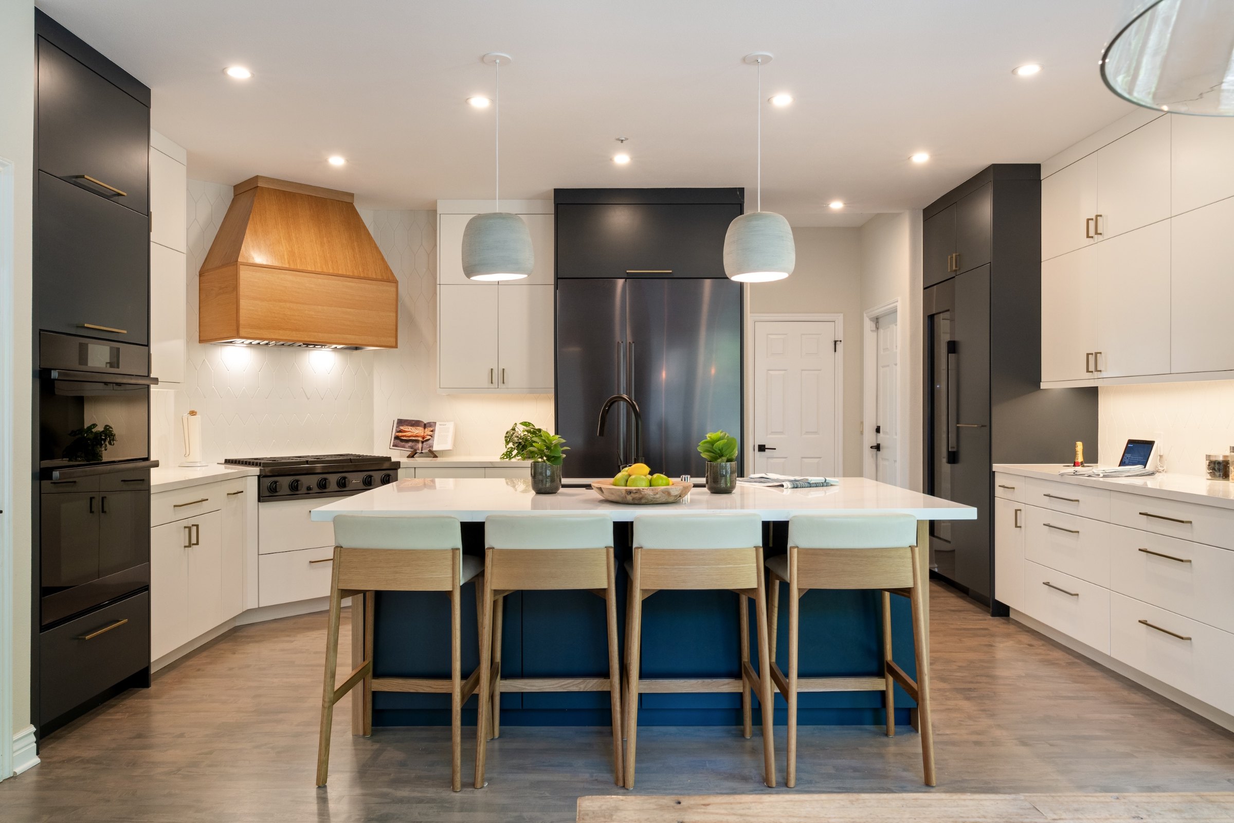 A white kitchen with a blue island, oak stools and a wood range hood, Marin County. Real estate photography by Lumiful Media