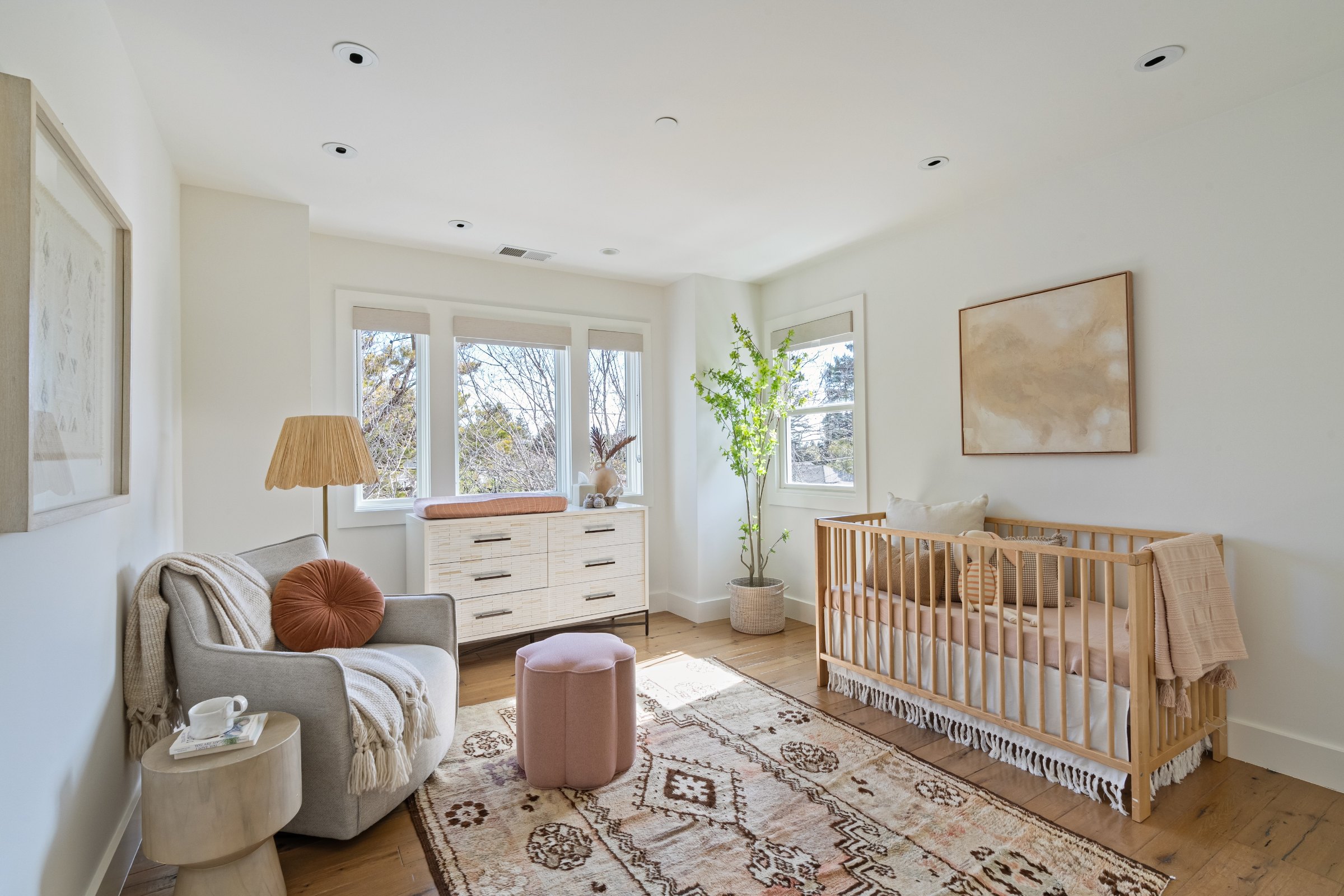 A nursery with a wooden crib and a reading chair by the windows, Marin County. Real estate photography by Lumiful Media