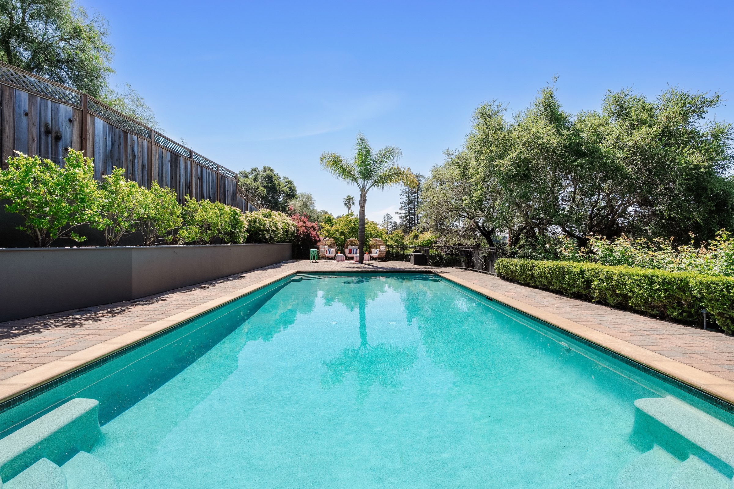 A long pool framed by hedges under a blue sky, Marin County. Real estate photography by Lumiful Media