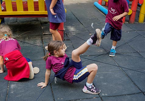Crianças brincam no pátio sobre piso emborrachado colorido da escola