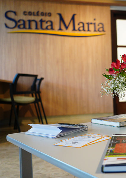 Recepção do Colégio Santa Maria, com o logotipo na parede de madeira